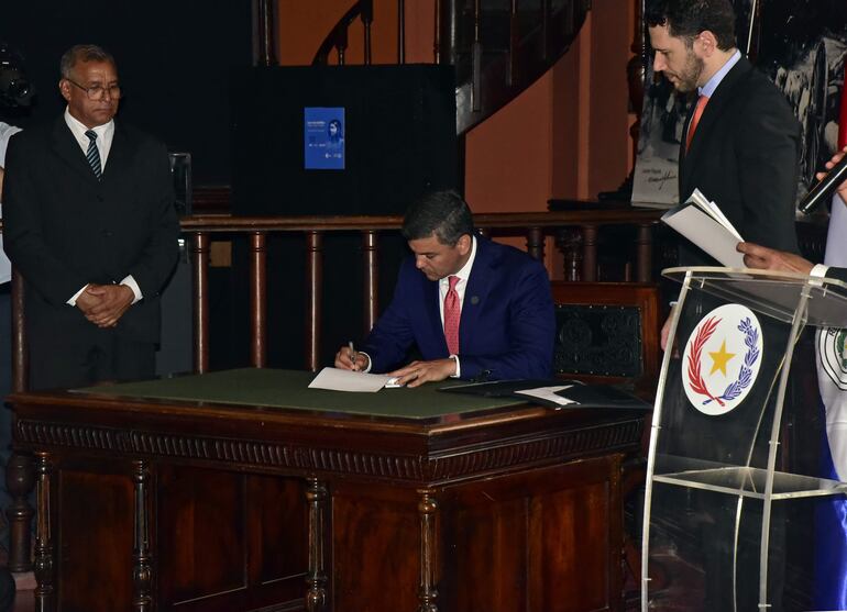 Firma de la ley de afrodescendientes en el Archivo Nacional por parte del Presidente de la República, Santiago Peña (c). A la izquierda, Guido Medina, secretario de la Red de Afrodescendientes del Paraguay y a la derecha, Ilo Moreno, asesor jurídico de la Presidencia de la República.