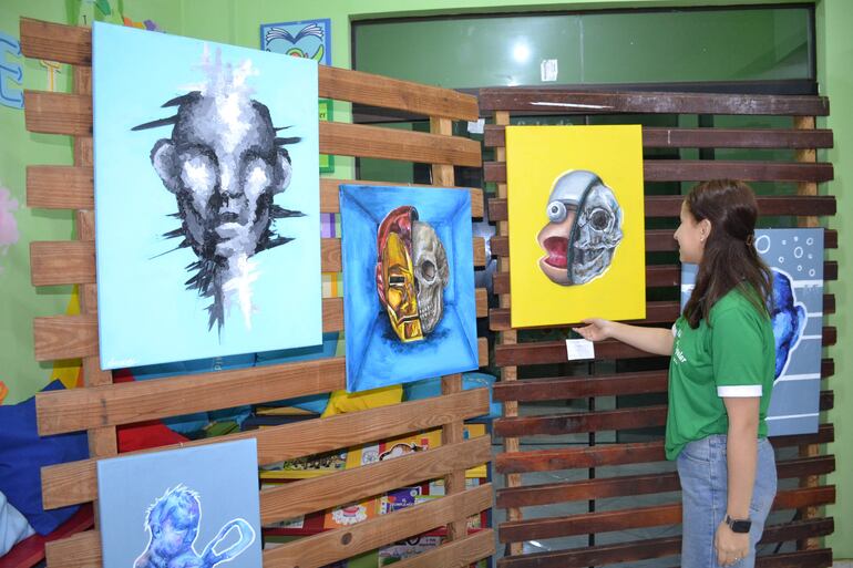 Una visitante contempla las obras de Leonardo Amarilla en la Biblioteca Popular de San Juan Nepomuceno.