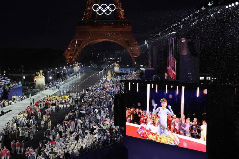 Las delegaciones llegan a Trocadero mientras los espectadores observan al cantante francés Philippe Katerine en una pantalla gigante. 