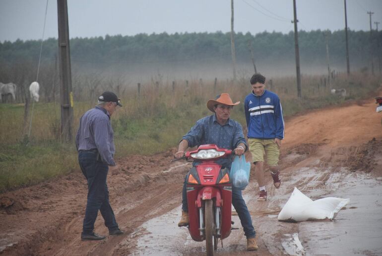 A un motociclista se le cayó una bolsa de harina en el barro al intentar cruzar el charco.