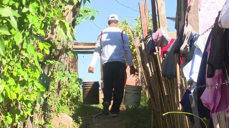 Un verdadero "vía crusis" sufren miles de familias a nivel país por la falta de agua. En la foto, un poblador del Bañado Sur llevando el vital líquido en dos baldes.