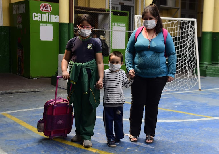 Madre, hijo e hija en la salida de la escuela básica N° 3 República del Brasil, munidos de tapabocas para protegerse de la contaminación a raíz de los incendios forestales.