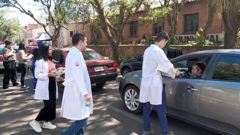 Estudiantes de medicina entregando materiales informativos a automovilistas que circulan por cercanías de la actividad.