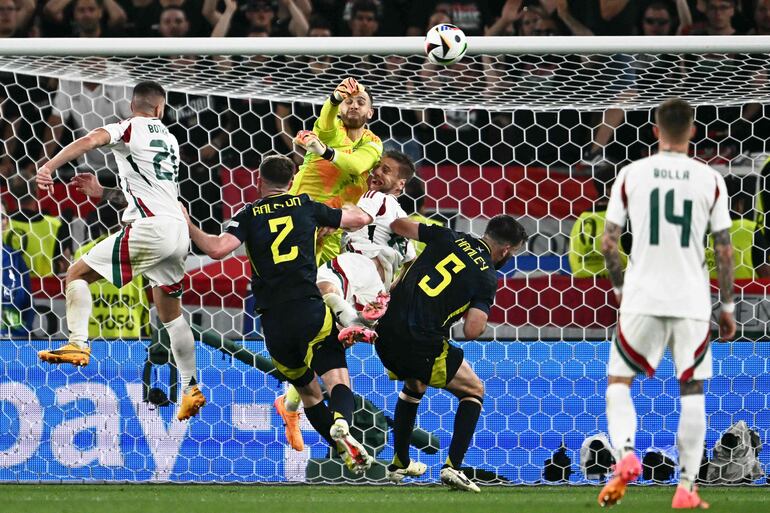 TOPSHOT - Hungary's forward #19 Barnabas Varga falls (C) on the pitch as Scotland's goalkeeper #01 Angus Gunn (up) punches out the ball during the UEFA Euro 2024 Group A football match between Scotland and Hungary at the Stuttgart Arena in Stuttgart on June 23, 2024. (Photo by Fabrice COFFRINI / AFP)