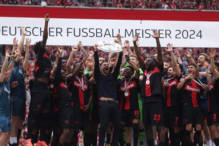 Leverkusen (Germany), 18/05/2024.- Leverkusen's head coach Xabi Alonso (C) lifts the Bundesliga trophy (Meisterschale) flanked by his players after the German Bundesliga soccer match of Bayer 04 Leverkusen against FC Augsburg, in Leverkusen, Germany, 18 May 2024. (Alemania) EFE/EPA/CHRISTOPHER NEUNDORF CONDITIONS - ATTENTION: The DFL regulations prohibit any use of photographs as image sequences and/or quasi-video.
