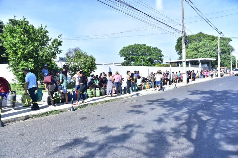 Con una temperatura superior a los 30ºC, personas forman una larga fila y esperan que su garrafa sea recargada.