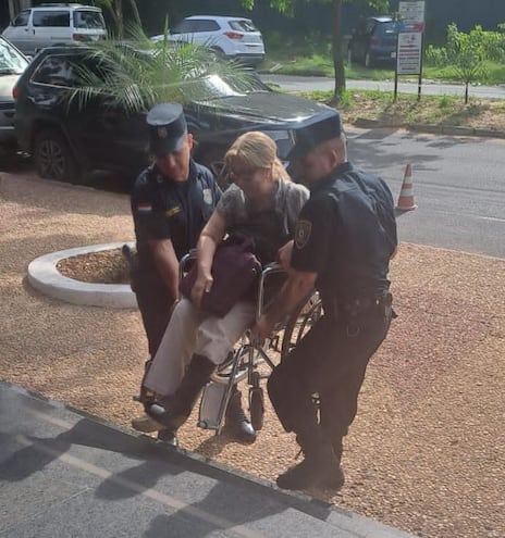 Dos policías alzan a la fiscala Hermenegilda Cubilla para poder ingresar al Juzgado de Lambaré. La sede judicial no cuenta con rampas.