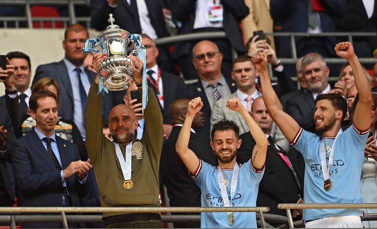 El español Pep Guardiola, técnico del Manchester City, celebra con el trofeo de la FA Cup en mano después de conquistar el certamen inglés contra el Manchester United en el estadio Wembley, en Londres. 