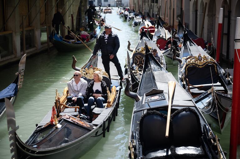 Un gondolero navega con dos clientes cerca de la Plaza de San Marcos en Venecia, el 25 de abril de 2024. La nueva estrategia para reducir el número de turistas que visitan este lugar declarado Patrimonio de la Humanidad por la UNESCO exige que los excursionistas paguen un billete de cinco euros para entrar en el histórico centro de la ciudad y comenzará el 25 de abril.