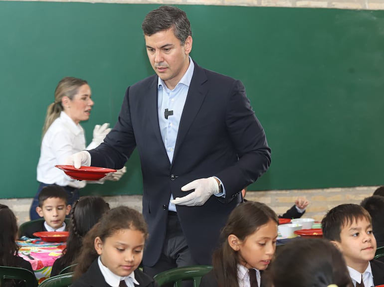 De guantes blancos. Santiago Peña sirve comida a los niños de la escuela Virgen del Carmen de Guarambaré. En el fondo se ve a su esposa Leticia Ocampos.