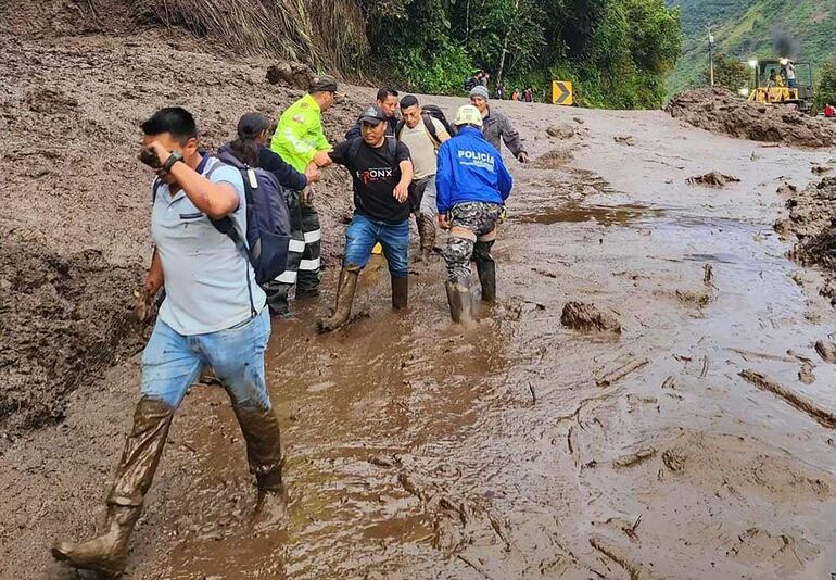 Agentes de policía ayudando a civiles en el lugar de un deslizamiento de tierra en Baños, Ecuador.