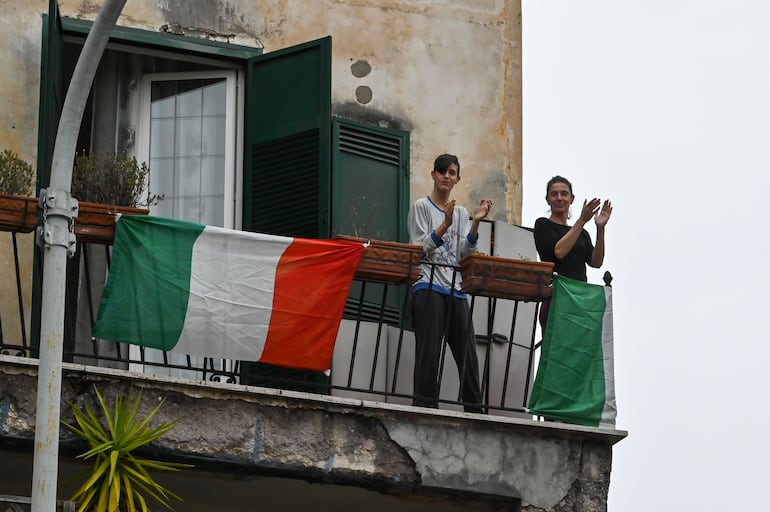 Las personas saludan y aplauden como parte de un flash mob "Un aplauso para Italia" (Un aplauso para Italia) en el distrito de Garbatella en Roma el 14 de marzo de 2020.