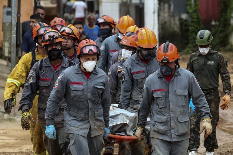 Bomberos llevan el cuerpo de las víctimas de un accidente en ruta que ocurrió al volcar un autobús de turismo en una carretera del estado de Bahía, Brasil.