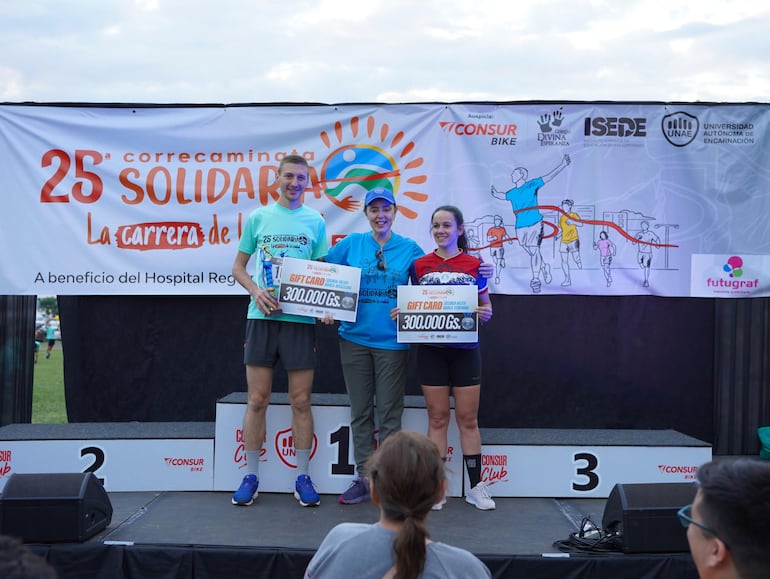 Orlando Elizeche y Verónica Flores, ganadores en sus respectivas categorías de la carrera de fondo de cinco kilómetros, recibieron sus premios de manos de la rectora de la UNAE, Nadia Czeraniuk.