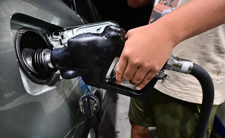 Un hombre carga combustible a un vehículo en una estación de servicio.