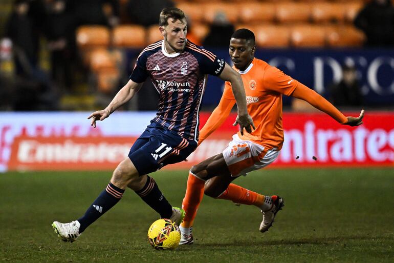 Chris Wood (i), delantero del Nottingham Forest, domina el balón ante el acoso de Marvin Ekpiteta, zaguero del Blackpool, durante el el encuentro que animaron ayer por la Copa de Inglaterra.