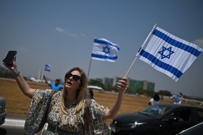 Una mujer sostiene una bandera de Israel durante una caravana en favor de la paz y el fin de la guerra, en vísperas del día en que se cumple un año del ataque de Hamas a Israel, este domingo en Brasilia 
