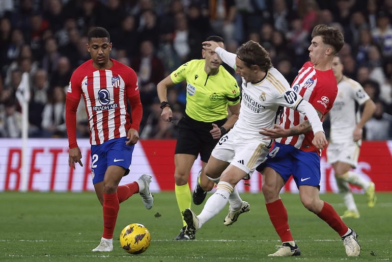 El centrocampista del Real Madrid Luka Modric (c) pelea un balón con Pablo Barrios (d) y Samuel Lino, ambos del Atlético, durante el partido de LaLiga de fútbol que Real Madrid y Atlético de Madrid han disputado este domingo en el estadio Santigo Bernabéu.