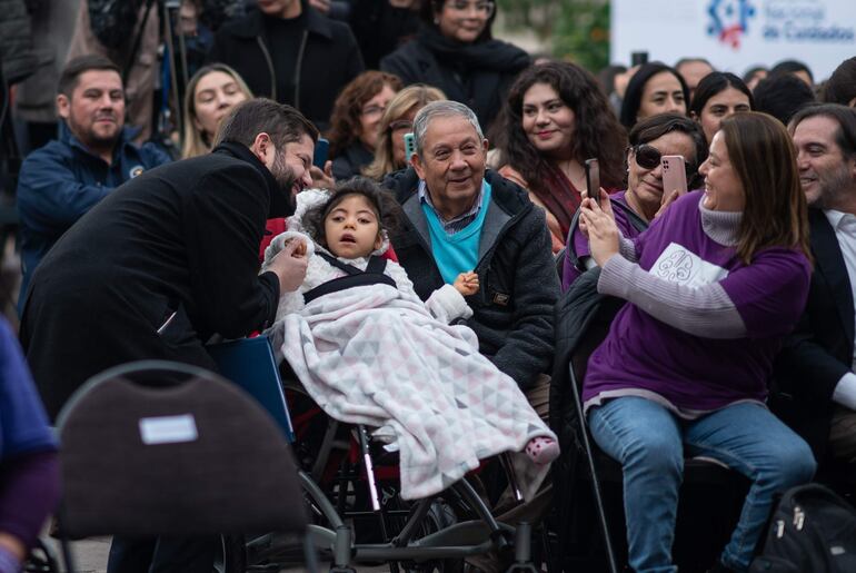 Fotografía cedida por Presidencia de Chile del mandatario, Gabriel Boric, mientras se toma una foto con una niña durante la firma del proyecto de ley que crea el Sistema Nacional de Cuidados.