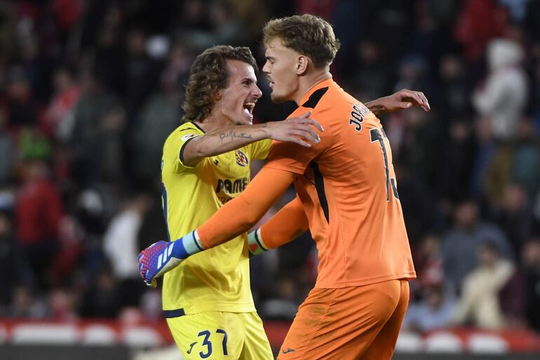 Los jugadores del Villarreal, el guardameta sueco, Filip Jorgensen (d) y Carlos Romero, celebran su victoria a la finalización del encuentro correspondiente a la jornada 11 de primera división que han disputado hoy lunes frente al Granada en el estadio Nuevo Los Carmenes de Granada.