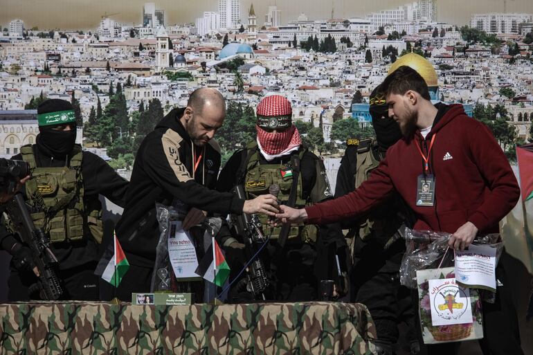 Militantes de Hamás y la Yihad Islámica se encuentran junto al rehén ruso-israelí Sasha (Alexander) Troufanov (d) y al rehén argentino-israelí Yair Horn (2i) antes de entregarlos al equipo de la Cruz Roja, en Khan Yunis, en el sur de la Franja de Gaza, el 15 de febrero de 2025. 
