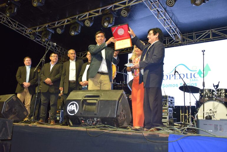 El intendente municipal Humberto Maidana (izquierda) entrega la placa de reconocimiento al presbítero Melanio Cardozo.