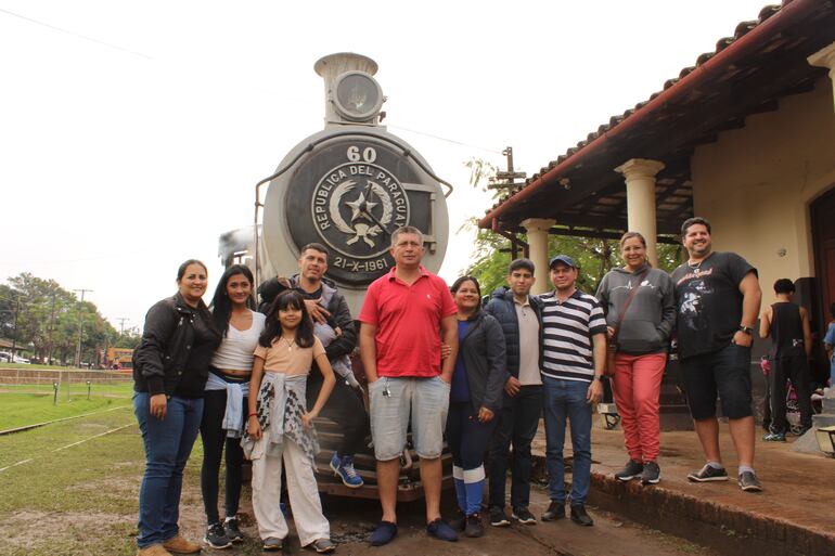 Turistas acompañados de sus familiares y amigos se toman fotografías frente a la emblemática locomotora.