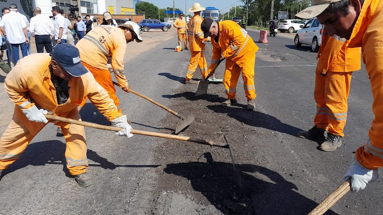 Obreros se disponen a reparar uno de los enormes baches de la ruta PY01, en presencia del presidente de la República.