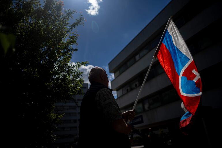 Un hombre con una bandera de Eslovaquia fuera del hospital donde está internado el primer ministro Robert Fico luego del atentado en su contra.