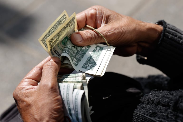  Fotografía de un cambista informal sosteniendo dolares este viernes en el centro de Asunción (Paraguay). El alza del dólar, atribuido por expertos a una demanda estacional y un "drenaje" de billetes verdes hacia Bolivia, ha llevado a un encarecimiento de los productos importados de la canasta básica EFE/ Juan Pablo Pino
