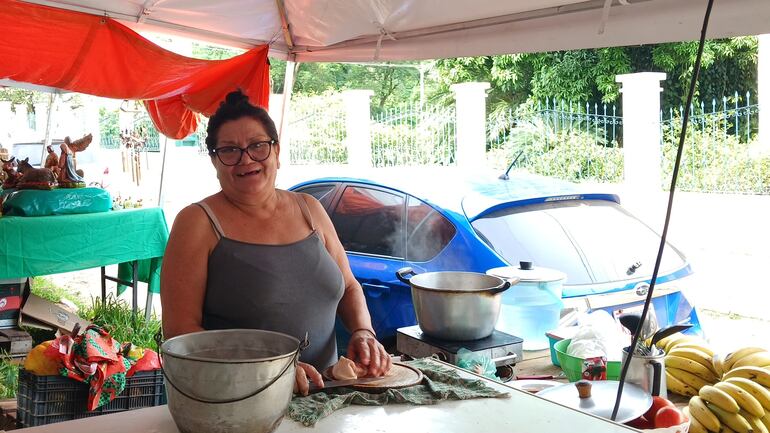 mujer con lentes posando, rodeada de frutas.