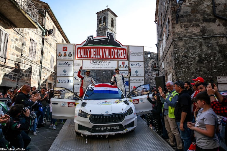 Fau Zaldívar y Marcelo Der Ohannesian, con la bandera paraguaya extendida sobre el parabrisas del Škoda Fabia RS Rally2, festejan  con el #1 de las manos una extraordinaria victoria. Los presentes en el podio final, ovacionaron a la dupla binacional en la ceremonia de premiación que fue muy especial.