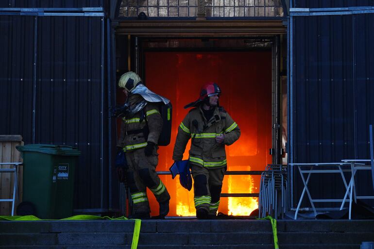 Copenhagen (Denmark), 16/04/2024.- Firefighters work at the main entrance of the old Stock Exchange (Boersen) after a fire hit the building, in Copenhagen, Denmark, 16 April 2024. A violent fire broke out in the building which is under renovation on the morning of 16 April. The building was erected in the 1620s as a commercial building by King Christian IV and is located next to the Danish parliament. (Dinamarca, Copenhague) EFE/EPA/Ida Marie Odgaard DENMARK OUT
