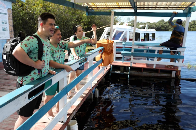 Jóvenes con discapacidades llegan a una sesión de terapia con delfines rosados (Inia geoffrensis) en un bote flotante en el río Negro, en Iranduba, Brasil.