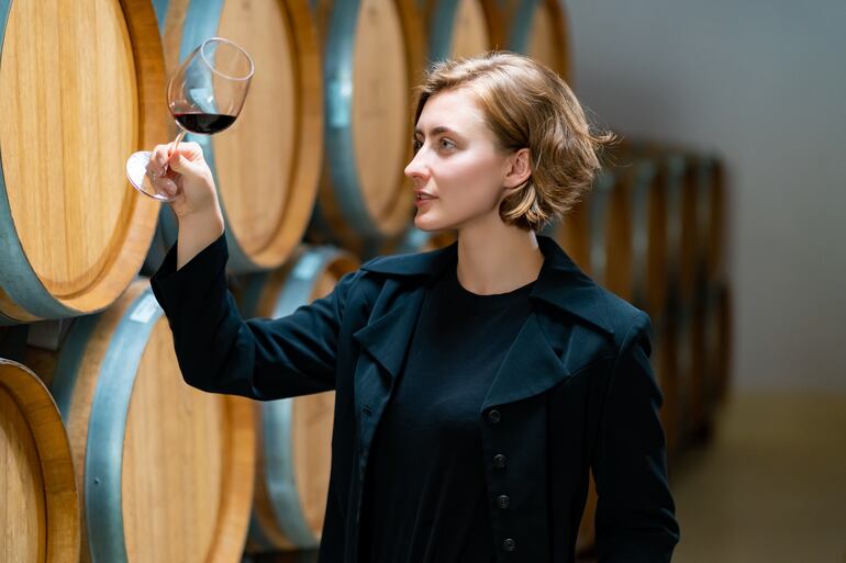 Una mujer observa las cualidades de un vino tinto en copa.