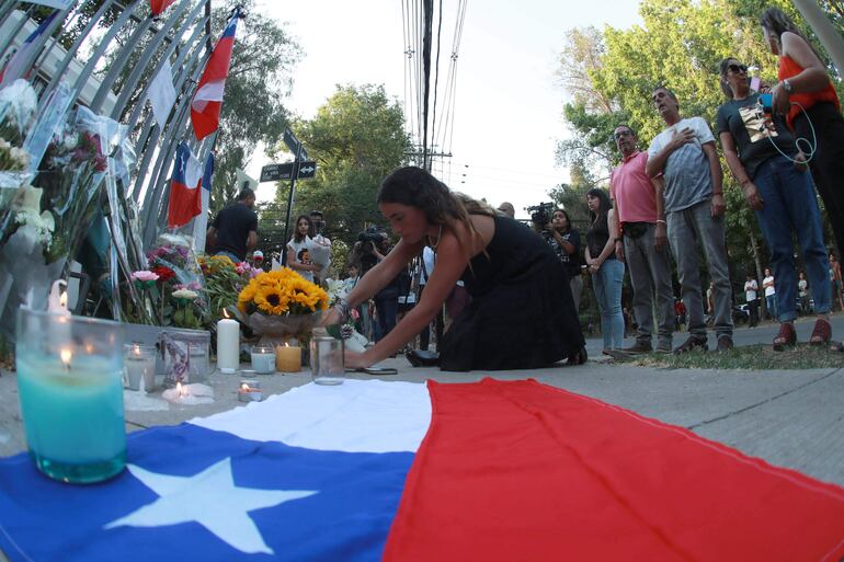 Un partidario del ex presidente chileno Sebastián Piñera deja una flor en un monumento conmemorativo en su honor frente a su casa en Santiago el 6 de febrero de 2024. El ex presidente de Chile, Sebastián Piñera, murió este martes 6 de febrero de 2024 en un accidente de helicóptero en Lago Ranco, una zona vacacional a 920 kilómetros al sur de Santiago, informó su oficina