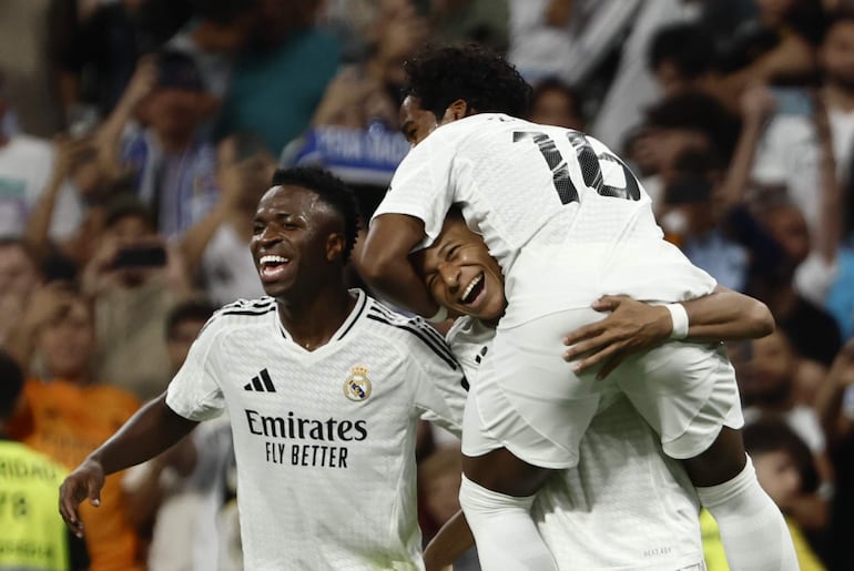 El delantero francés del Real Madrid, Kylian Mbappé (c), celebra con sus compañeros, los brasileños Vinicius (i) y Endrick, el cuarto gol del equipo madridista durante el encuentro correspondiente a la sexta jornada de Laliga EA Sports que disputan hoy sábado Real Madrid y Espanyol en el estadio Santiago Bernábeu, en Madrid.