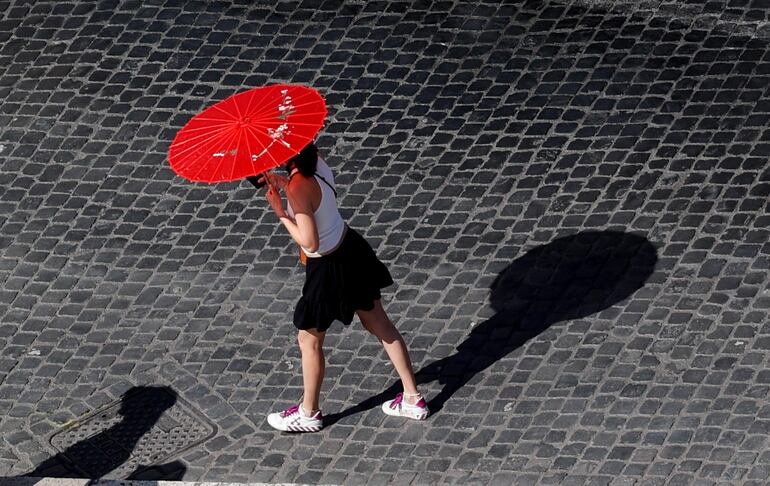 Una mujer porta una sombrilla para protegerse del sol en un caluroso día, en Roma. Las previsiones meteorológicas alertan de temperaturas de 40 grados en toda Italia. 
