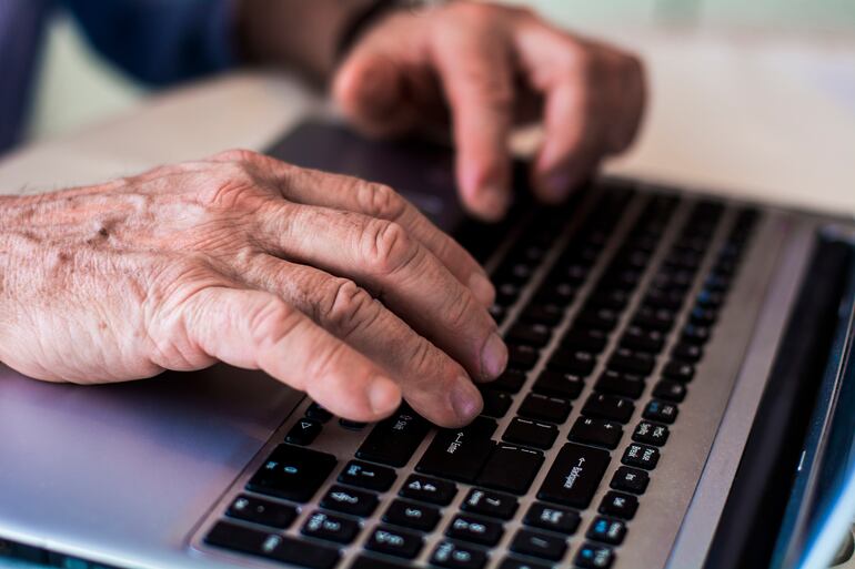 mano de un adulto mayor anciano tecleando en una computadora.