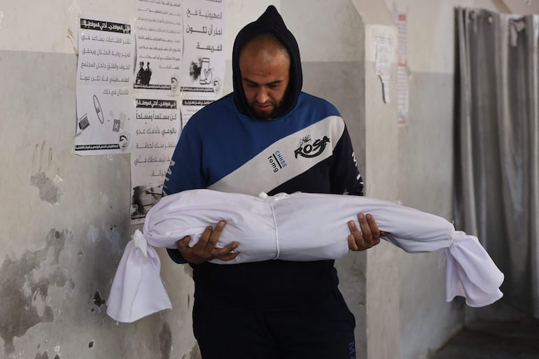 Un hombre lleva en brazos el cuerpo de un niño fallecido a causa de un bombardeo israelí en la Ciudad de Gaza, el jueves.