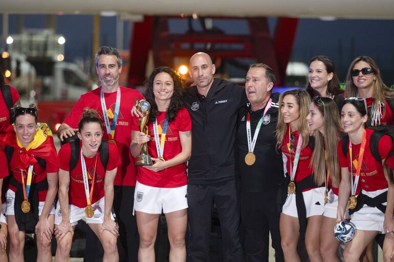 Las jugadoras de la selección española de fútbol, nueva campeona del Mundo, acompañadas por su entrenador Jorge Vilda y por el presidente de RFEF Luis Rubiales (pelado, en el centro), posan con el trofeo a su llegada al aeropuerto de Barajas, este lunes en Madrid.