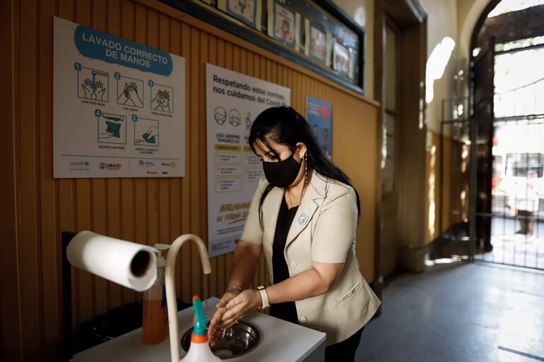 Una profesora se lava las manos al ingresar a la Escuela Celsa Speratti, en Asunción durante la pandemia del Covid en el 2021.