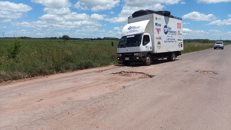 Un camión repartidor de mercaderías a punto de pasar un enorme bache del ramal.