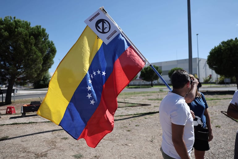 Un manifestante con una bandera de Venezuela y una imagen de "prohibido" Maduro.