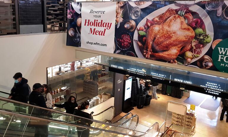 Unas personas pasan frente a un cartel de ofertas de pavo por el Día de Acción de Gracias en un supermercado de Nueva York (EE.UU). Pavos veganos, cena con amigos en lugar de con la familia y reflexiones sobre el origen colonialista de la fiesta: los estadounidenses se preparan para su gran celebración del año, Acción de Gracias, un encuentro en el que sigue prevaleciendo la tradición aunque cada vez cuente con más alternativas.