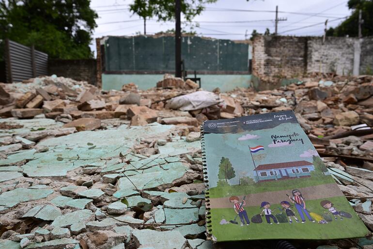 Un cuaderno del kit escolar reposa entre los escombros donde Engineering SA debe levantar una sala de clases, en la escuela Delfín Chamorro del barrio Roberto L. Petit.