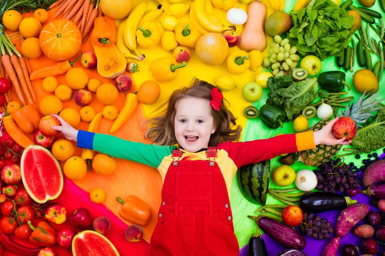 Niña sobre frutas y hortalizas.