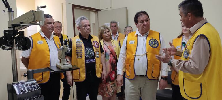 El presidente del club de Leones de Fernando de la Mora, León César Rubén Romero, y escucha atentamente el Presidente Internacional, Fabrizio Oliveira, dentro de uno de los consultorios oftalmológicos del Sanatorio Angelita torales de Zaracho.