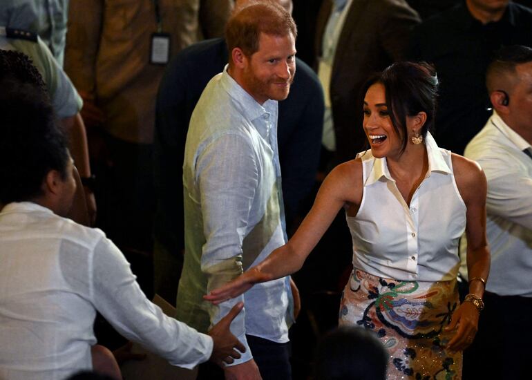 El príncipe Harry de Gran Bretaña, duque de Sussex, y su esposa Meghan Markle saludan a los asistentes a su llegada al foro Mujeres y poder afro, en el Teatro Municipal de Cali, Colombia. (RAUL ARBOLEDA / AFP)