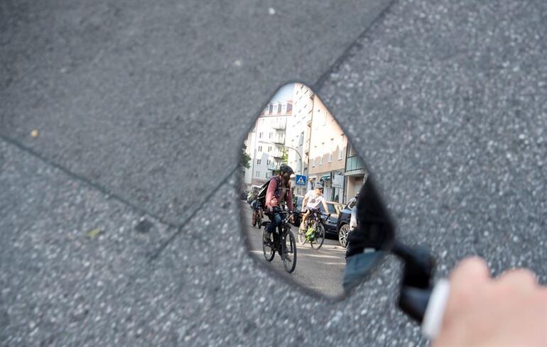 Un ciclista observa a otro en el espejo retrovisor de su bicicleta.